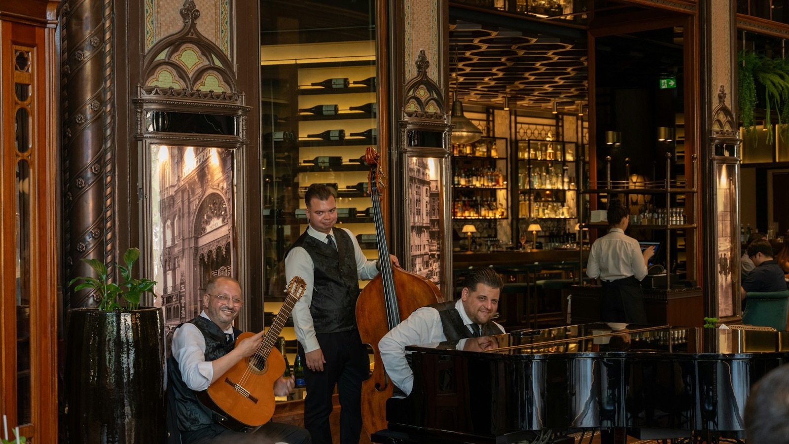 A live trio playing guitar, upright bass, and piano in a restaurant dining room, one of the restaurant event ideas that fills a slow night